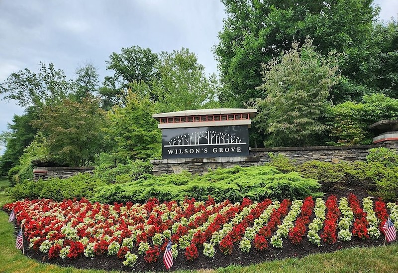 The Wilson's Grove entrance sign behind rows of red and white flowers
